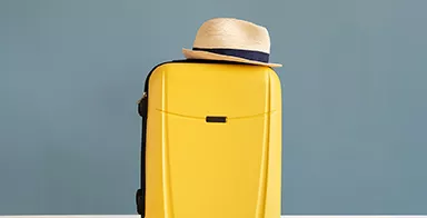 Photo d'une valise surplombée d'un chapeau de paille