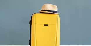 Photo d'une valise surplombée d'un chapeau de paille