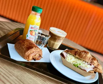 Photo d'un croissant jambon beurre, d'un petit pain et d'un jus d'orange